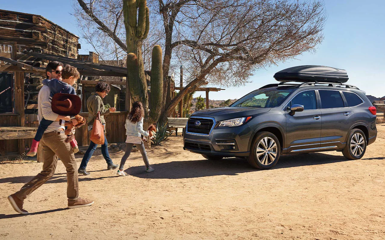 Family on desert vacation walking back to their Subaru Ascent